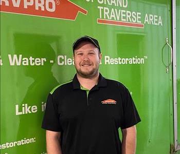Male wearing a cap standing in front of green SERVPRO vehicle