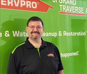 Male brown haired standing in front of green SERVPRO vehicle