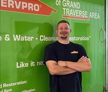 Male brown haired standing in front of green SERVPRO vehicle